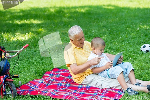 Image of grandfather and child in park using tablet