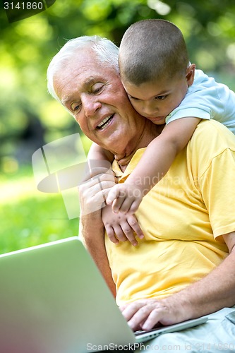 Image of grandfather and child using laptop