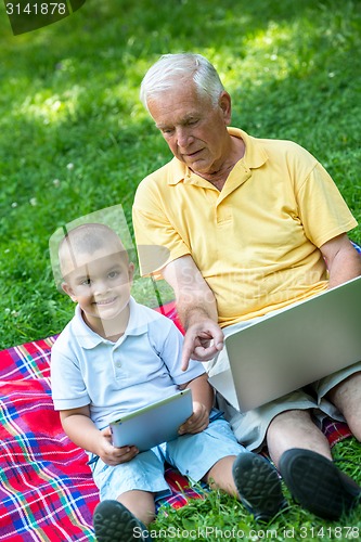 Image of grandfather and child in park using tablet