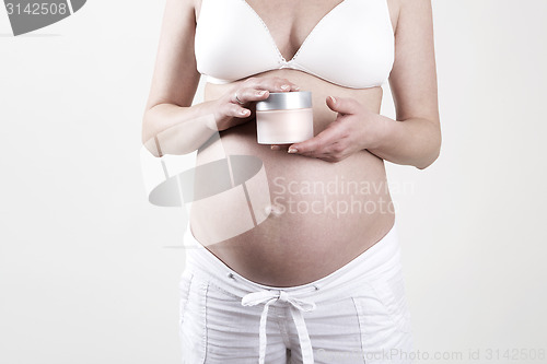 Image of Pregnant woman holding creme in her hands