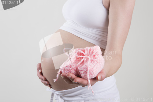 Image of Pregnant woman holding pink baby shoes in her hands