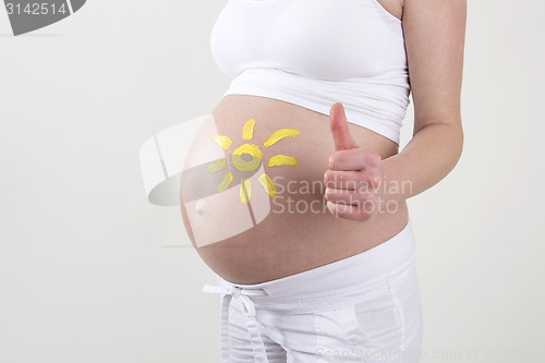 Image of Pregnant woman with yellow sun painted on her belly