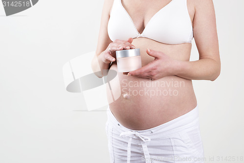 Image of Pregnant woman holding creme in her hands