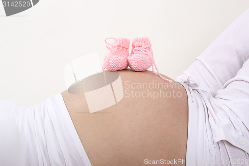 Image of Pregnant woman with pink baby shoes on her belly