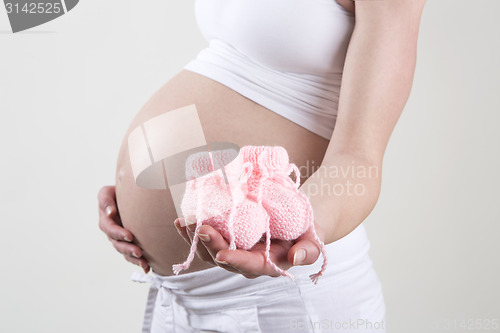 Image of Pregnant woman holding pink baby shoes in her hands