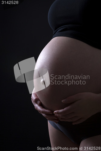 Image of Pregnant woman in front of black background