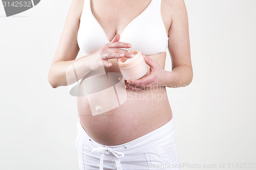 Image of Pregnant woman putting creme on her belly