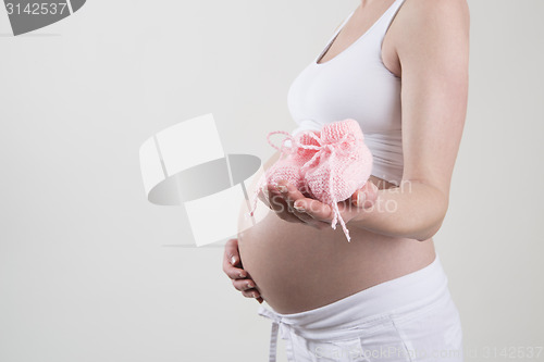 Image of Pregnant woman holding pink baby shoes in her hands