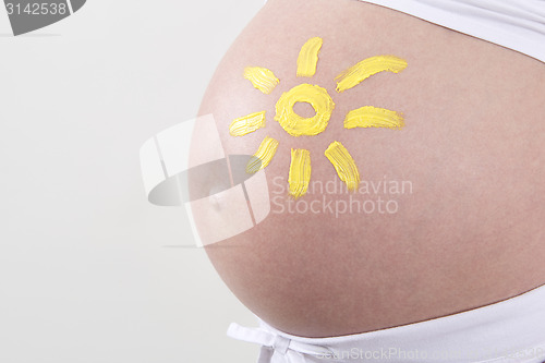 Image of Pregnant woman with yellow sun painted on her belly