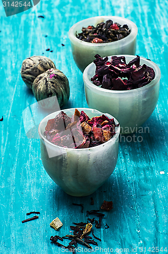 Image of variety of dry tea leaves in jade stacks on wooden background