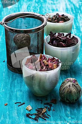 Image of variety of dry tea leaves in jade stacks on wooden background