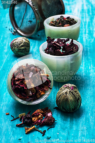 Image of variety of dry tea leaves in jade stacks on wooden background