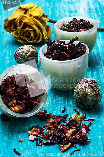 Image of variety of dry tea leaves in jade stacks on wooden background