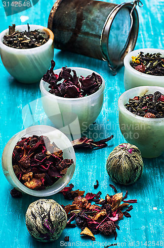 Image of variety of dry tea leaves in jade stacks on wooden background