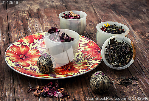 Image of variety of dry tea leaves in jade stacks on wooden background