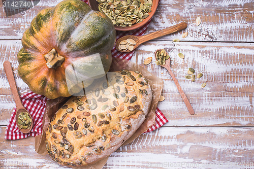 Image of Rustic style baked bread with seeds and pumpkin on wood