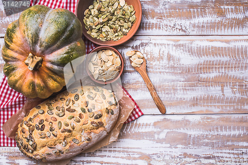 Image of Newly baked bread with seeds and pumpkin on wooden table