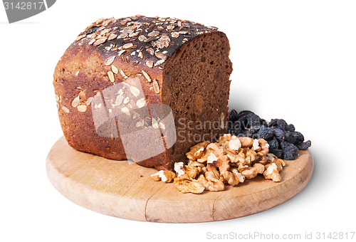 Image of Bread with seeds on wooden board with raisins and nuts