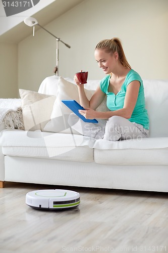 Image of happy woman with tablet pc drinking tea at home