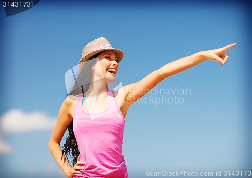 Image of girl in hat showing direction on the beach