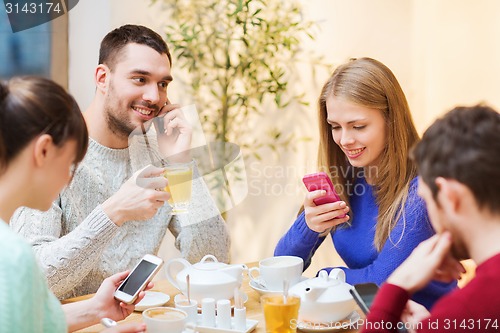 Image of group of friends with smartphones meeting at cafe