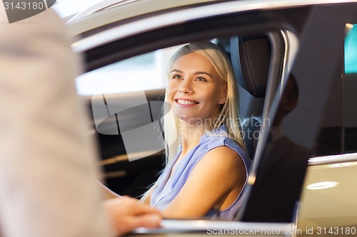 Image of happy woman with car dealer in auto show or salon