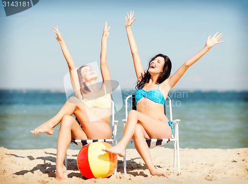 Image of girls sunbathing on the beach chairs