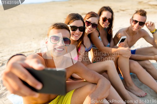 Image of friends with smartphones on beach