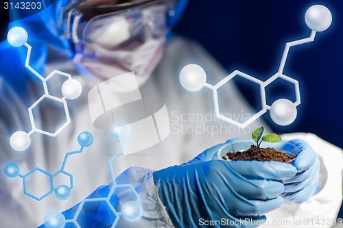 Image of close up of scientist with plant and soil in lab