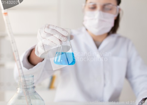 Image of close up of woman with flask making test in lab