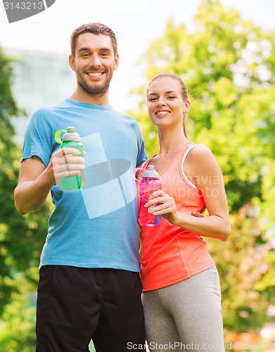 Image of smiling couple with bottles of water outdoors