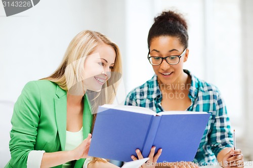 Image of smiling student girls reading book at school