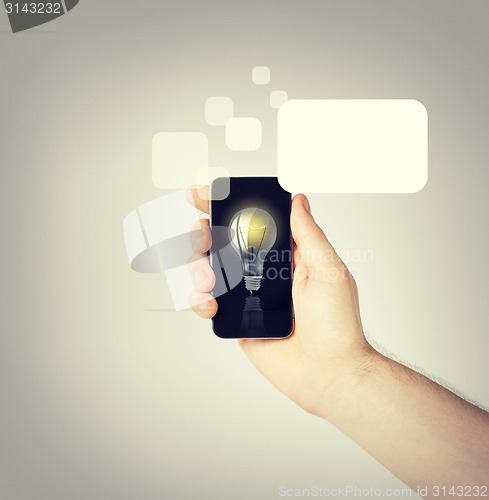 Image of man hand holding smartphone with light bulb