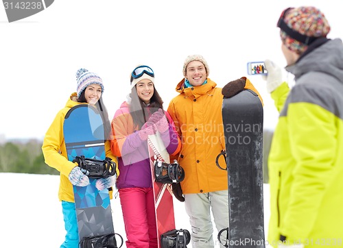 Image of happy friends with snowboards and smartphone