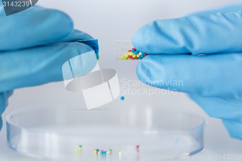 Image of close up of scientist hands holding pill in lab