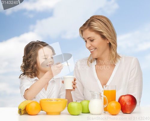 Image of happy mother and daughter eating breakfast