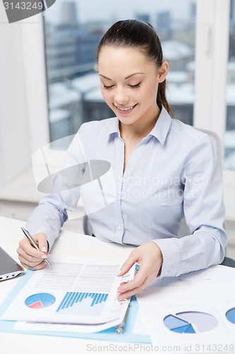 Image of businesswoman with laptop and charts in office