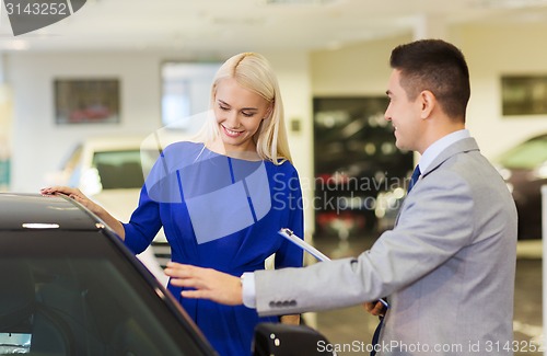 Image of happy woman with car dealer in auto show or salon