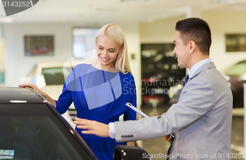 Image of happy woman with car dealer in auto show or salon