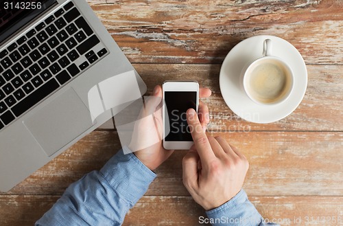 Image of close up of hands with laptop and smartphone