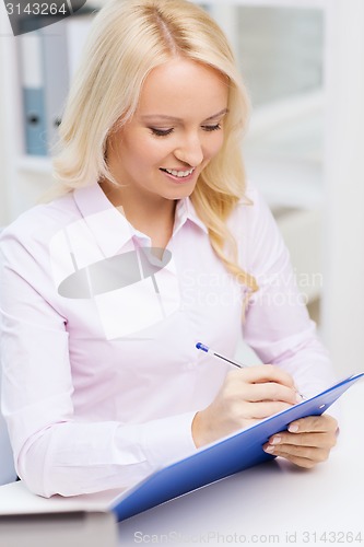 Image of smiling businesswoman with clipboard in office