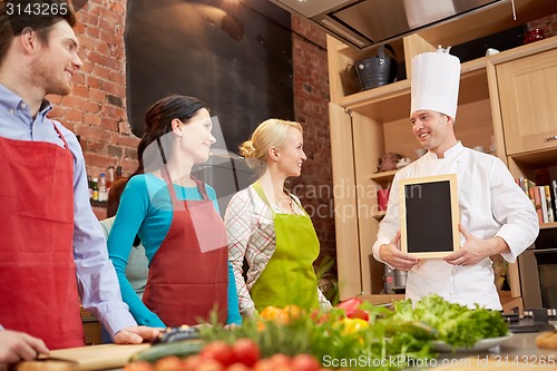 Image of happy friends and chef cook with menu in kitchen