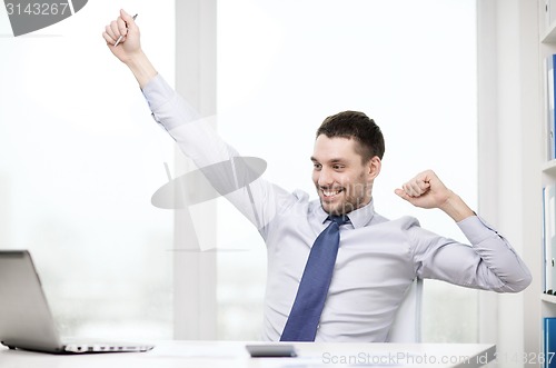 Image of smiling businessman with laptop and documents