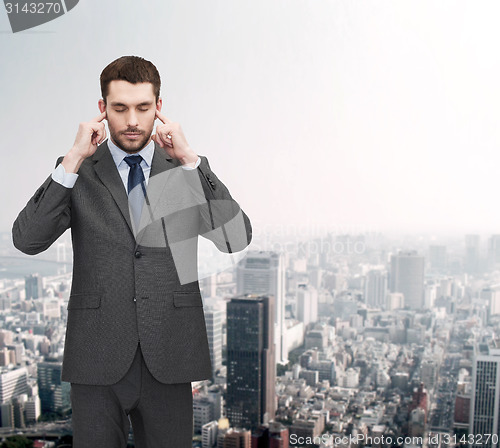 Image of annoyed businessman covering ears with his hands