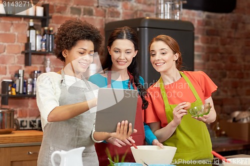 Image of happy women with tablet pc cooking in kitchen