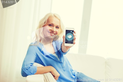 Image of smiling woman with smartphone at home