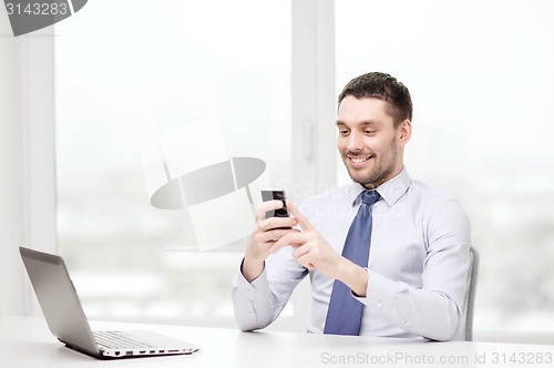 Image of businessman with laptop and smartphone at office