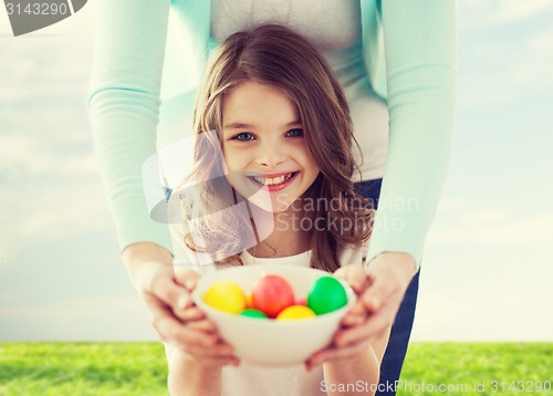 Image of smiling girl and mother holding colored eggs