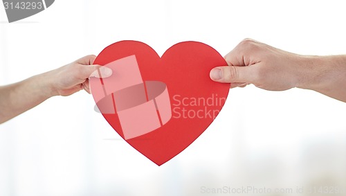 Image of close up of child and male hands holding red heart