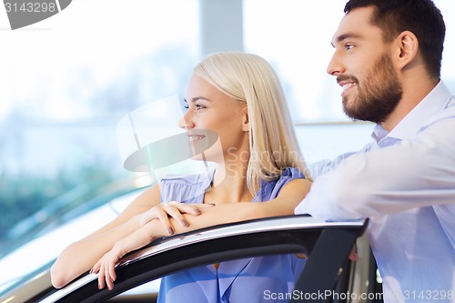 Image of happy couple buying car in auto show or salon